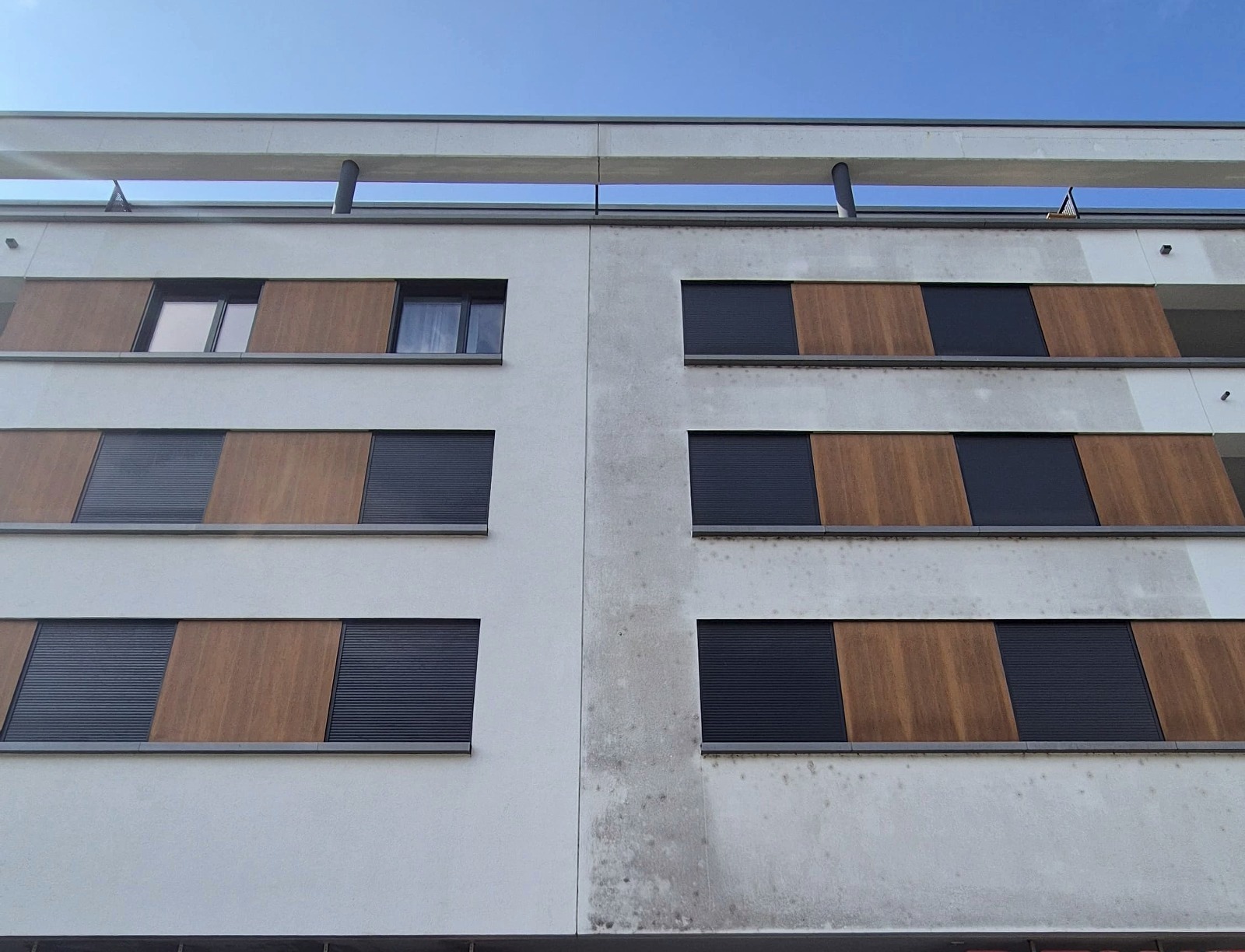 Fassade eines Wohn- und Geschäftshauses: links die gereinigte, weiße Fläche, rechts die noch grau verschmutzte, dazwischen eine scharfe senkrechte Kante an der Gebäudefuge
