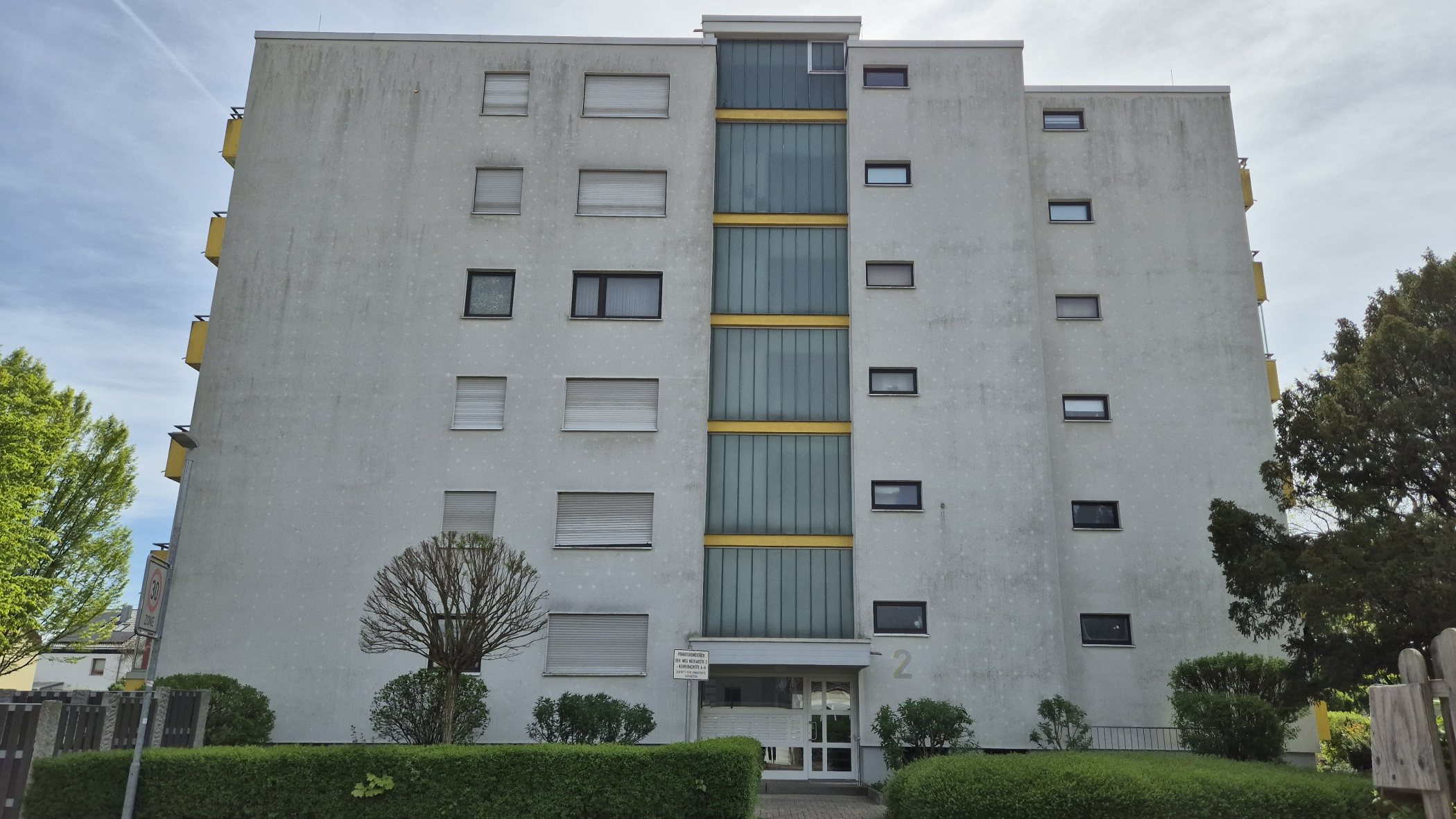 Sechsgeschossige Wohnanlage mit grau verschmutzter Fassade vor der Reinigung